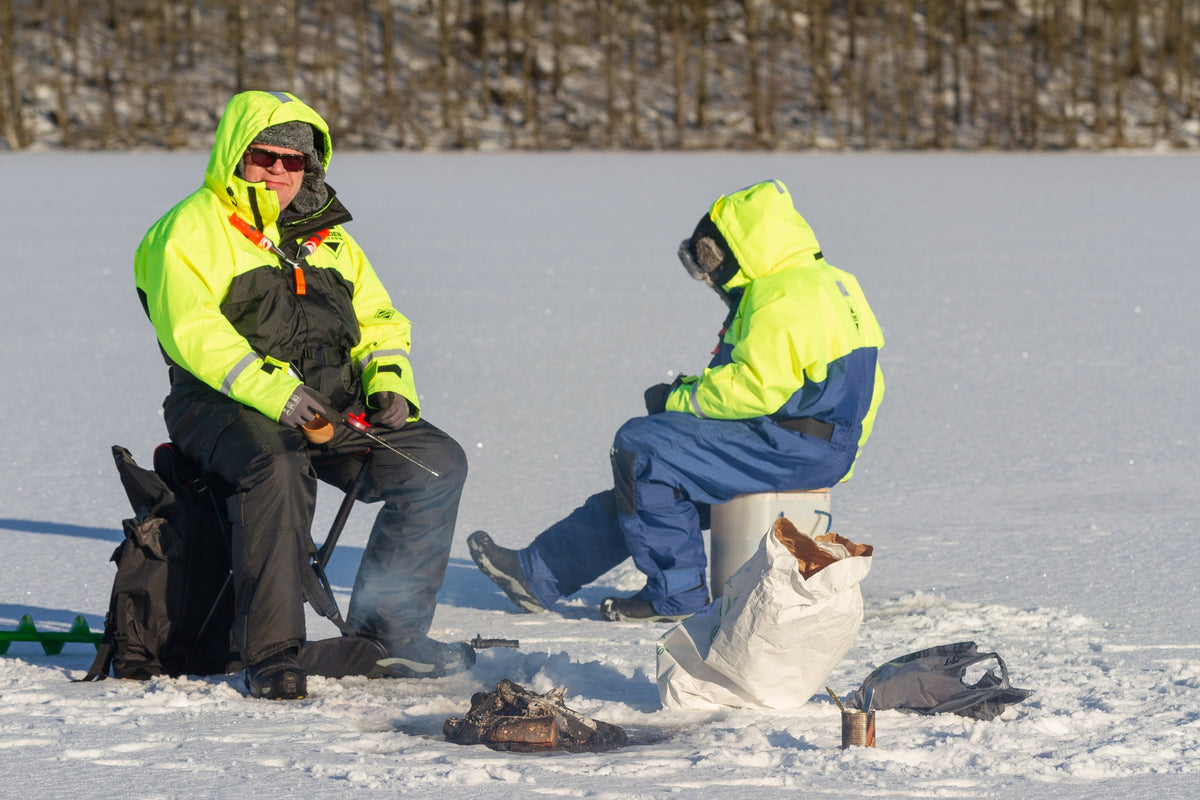 Kaksi miestä pilkillä jäätyneellä järvellä talvella